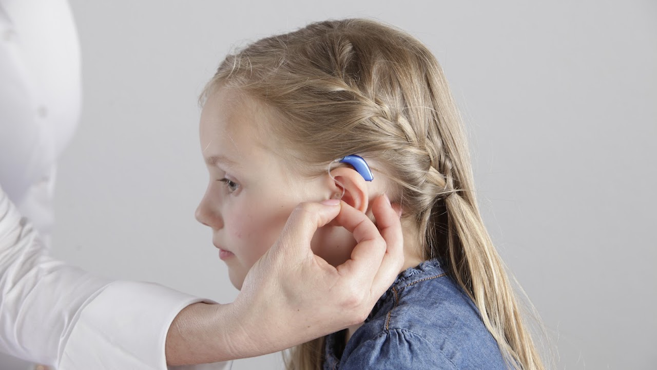 Little girl with hearing aid having her ear checked