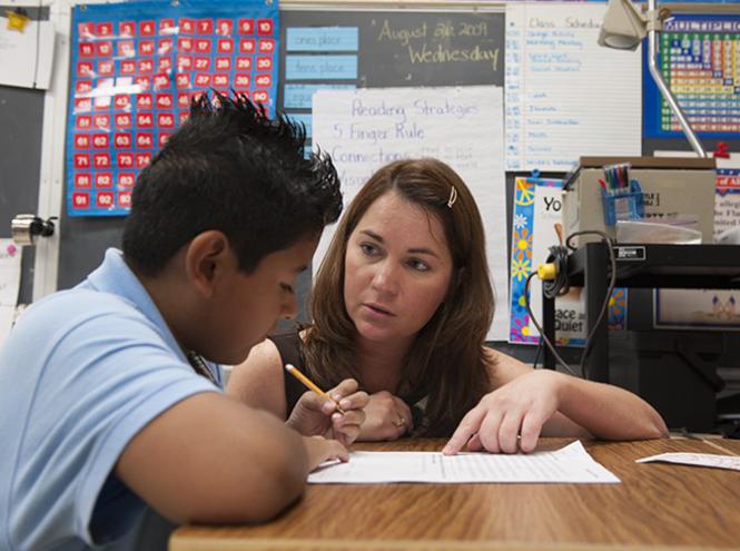 Teacher assisting student with writing assignment 