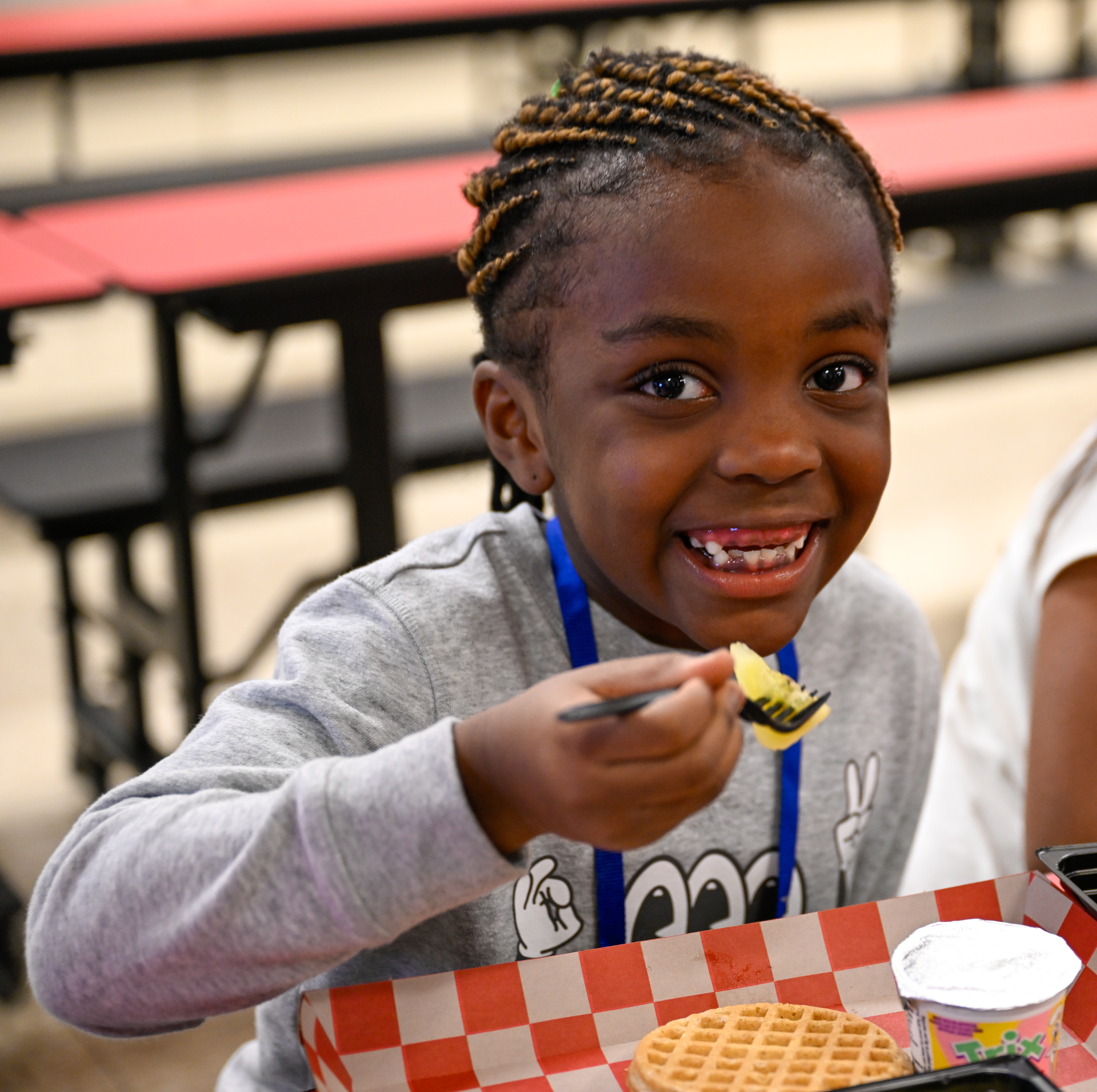 Student smiles while eating lunch in school cafeteria