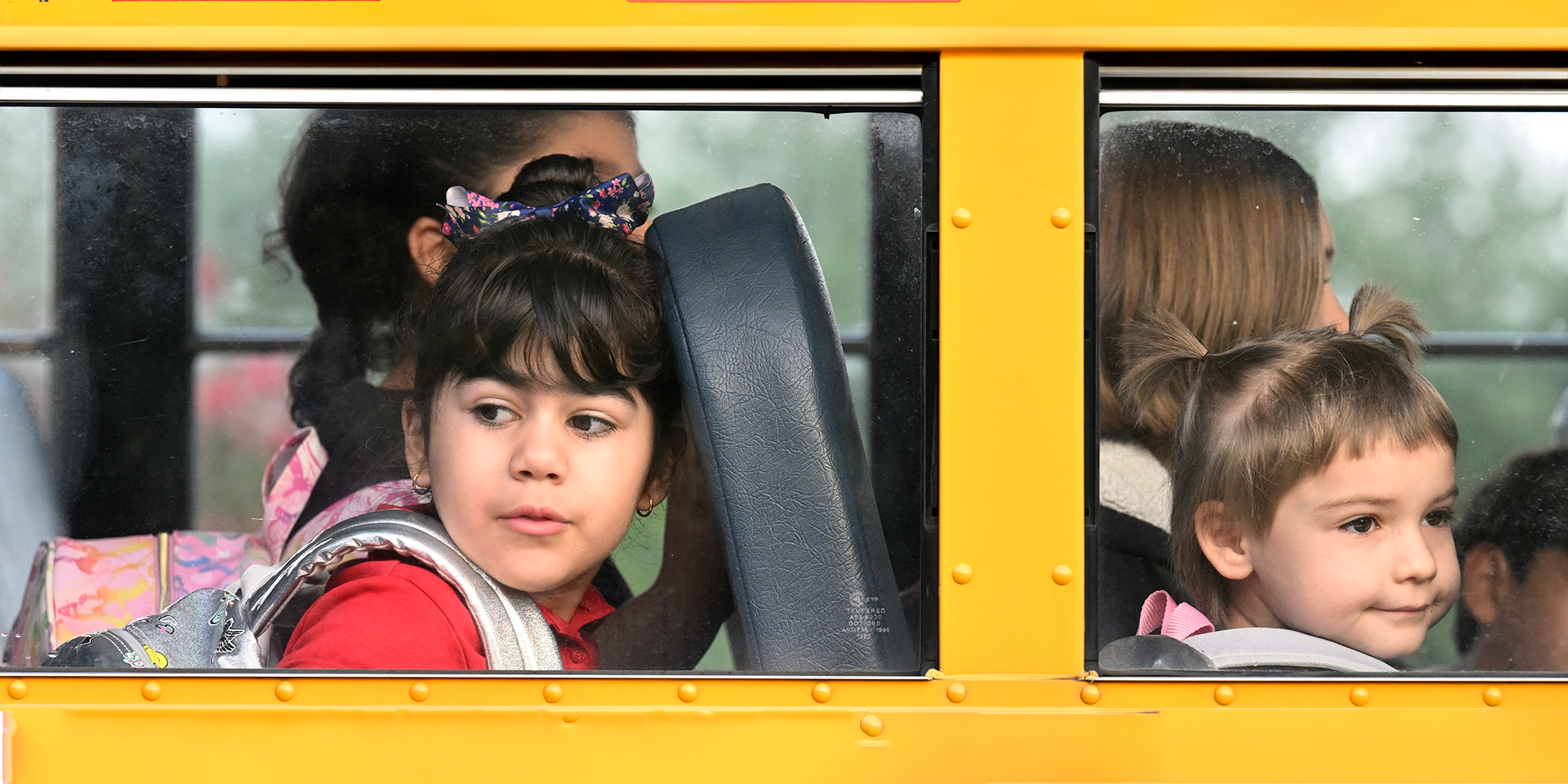 Two students looking out school bus window