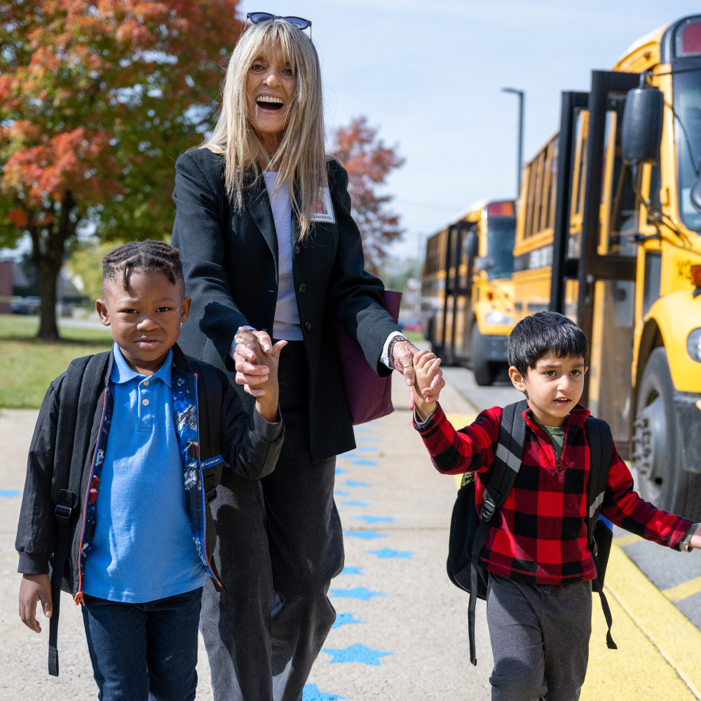 Woman walking two kids off bus