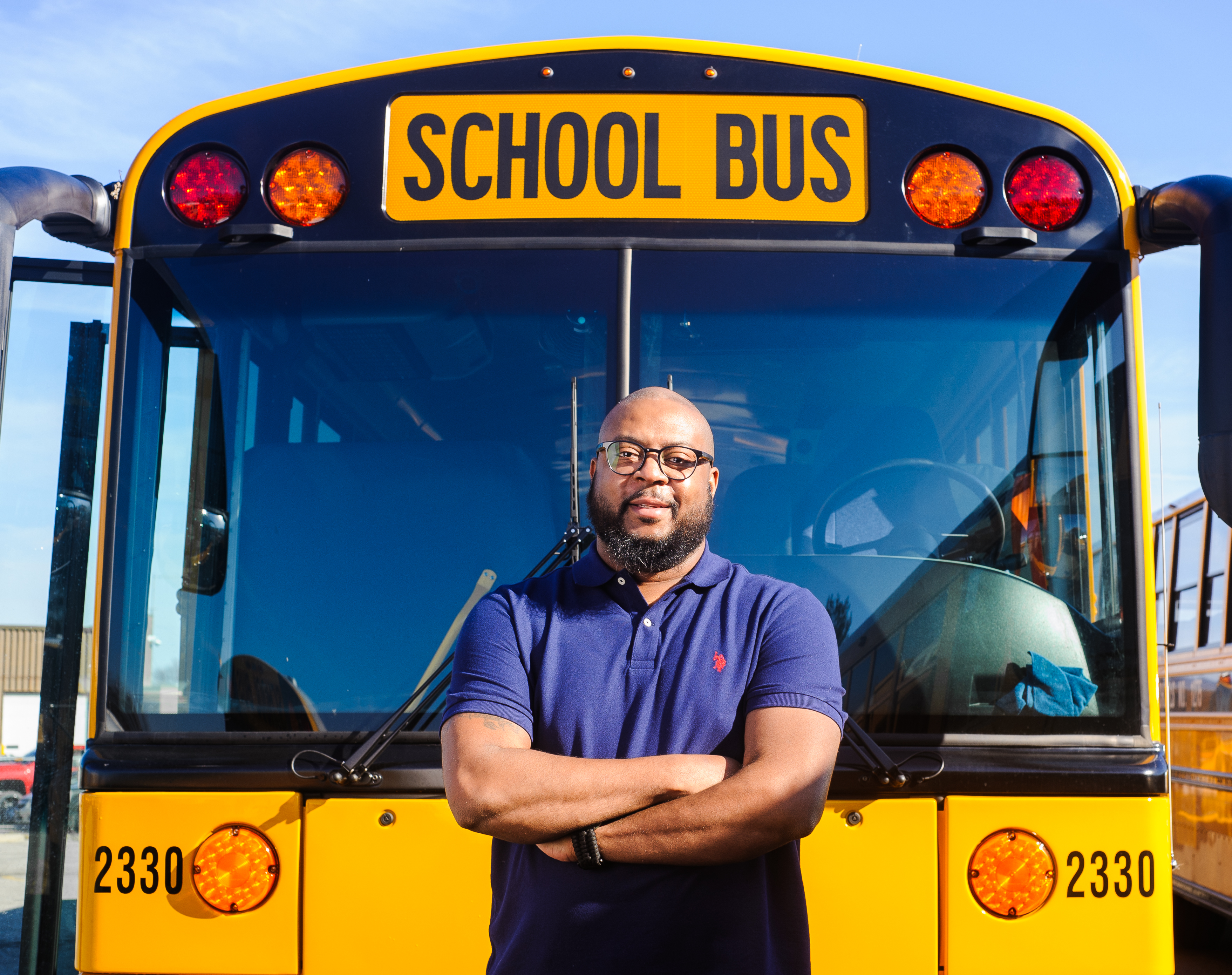 Bus driver in front of bus