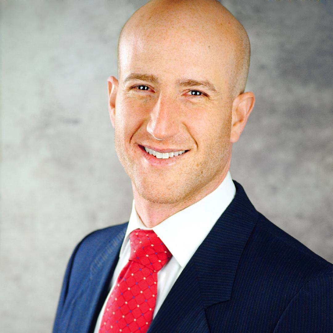 Man smiling in blue suit in front of grey background