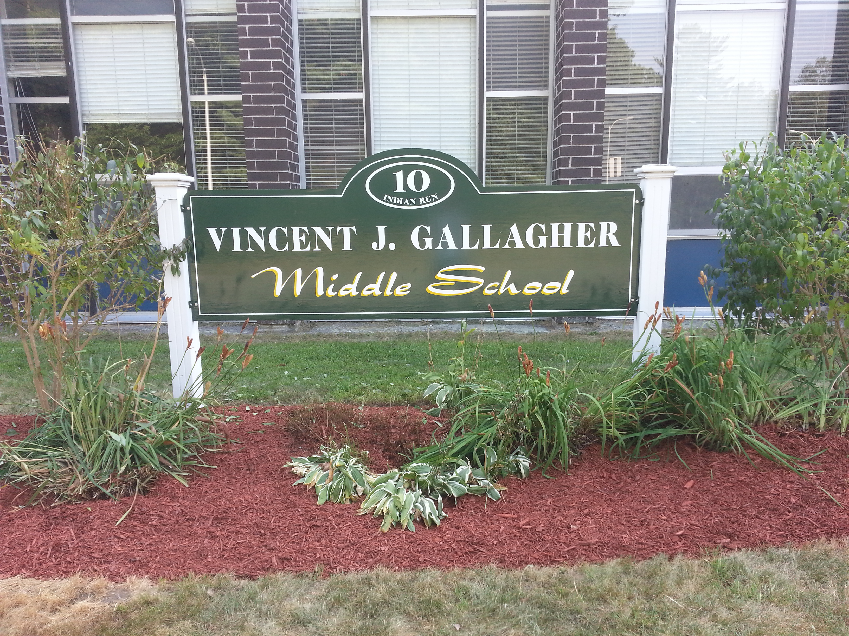 Green sign with white and yellow lettering reading Vincent J. Gallagher Middle School