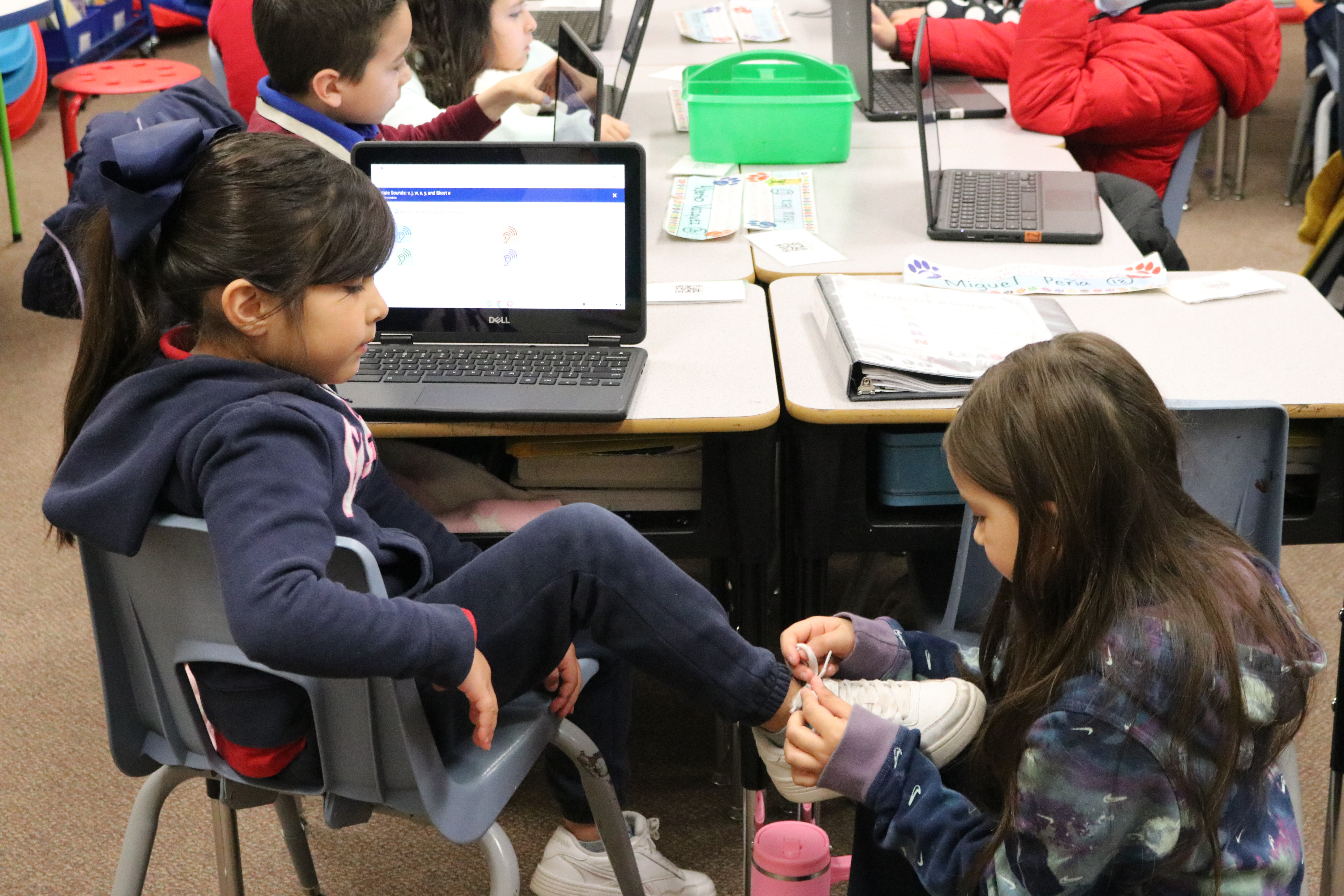 Student helping another student with tying their shoe.