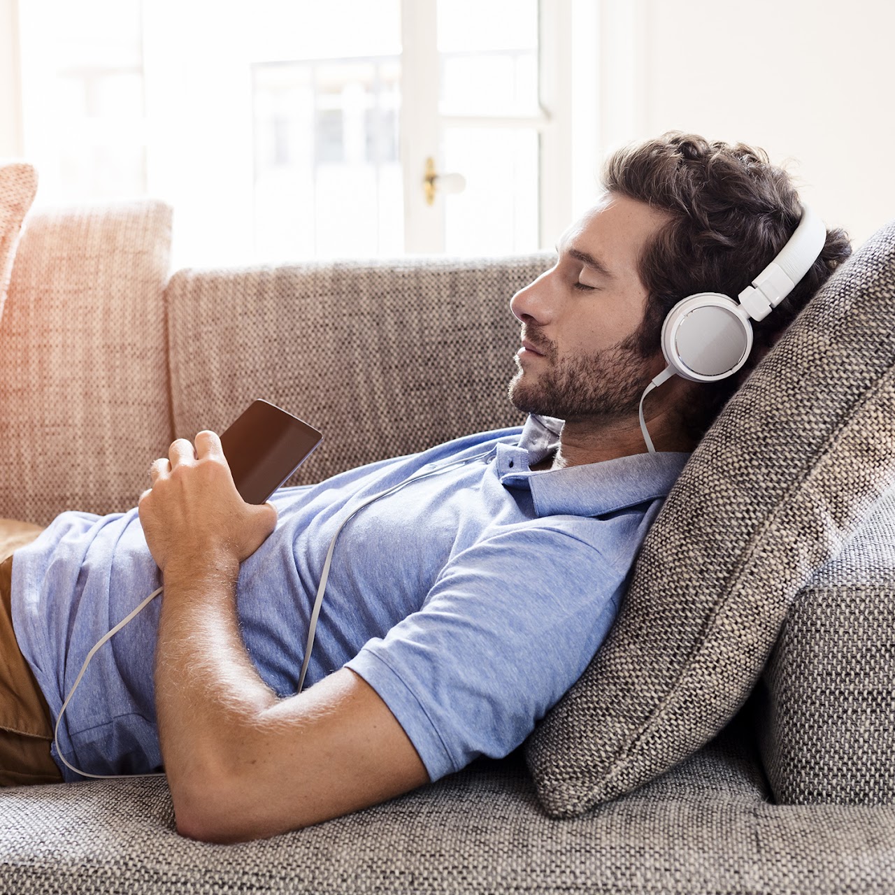 person laying down on a couch, listening to music