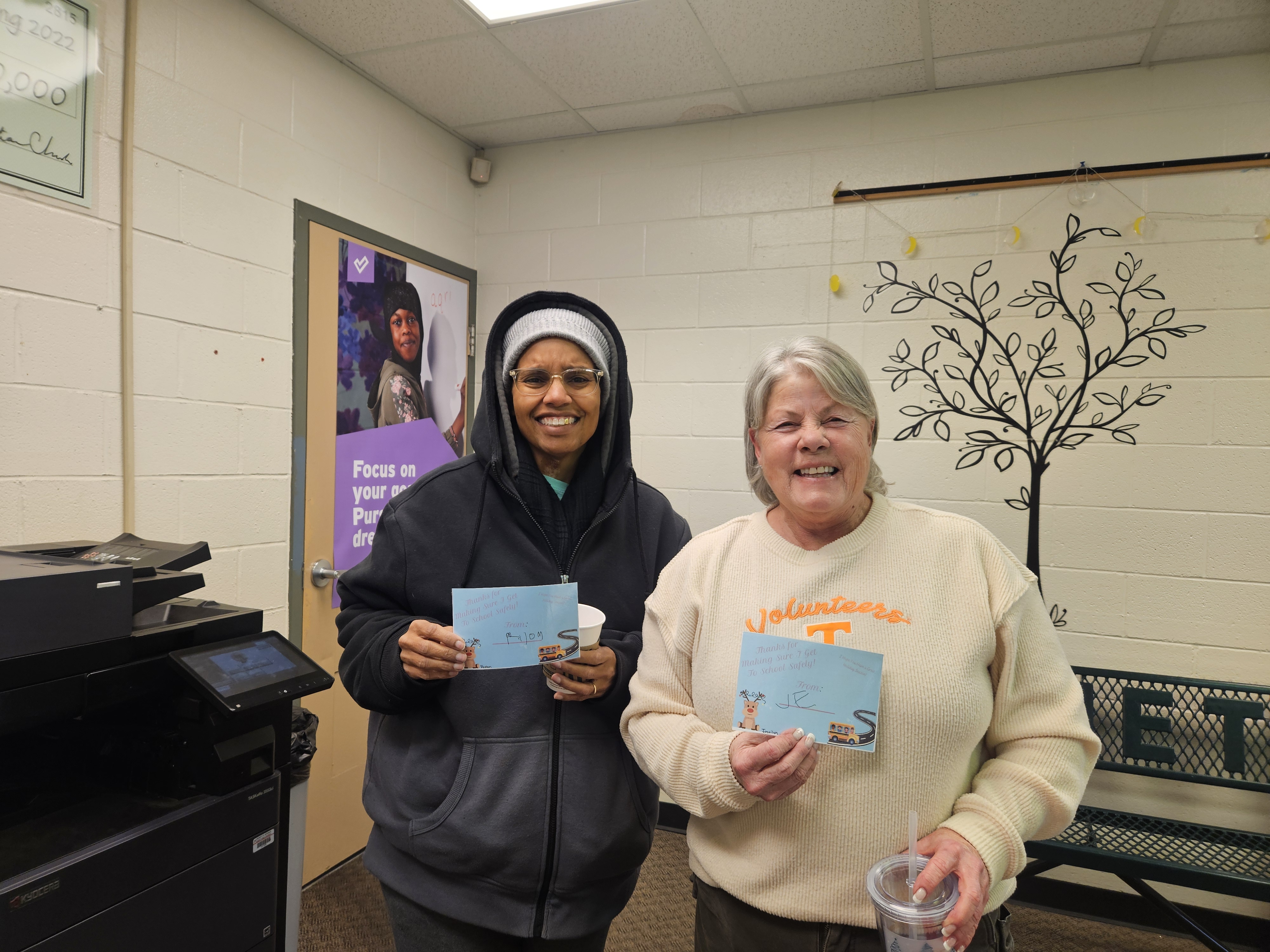 Two people standing together holding cards.