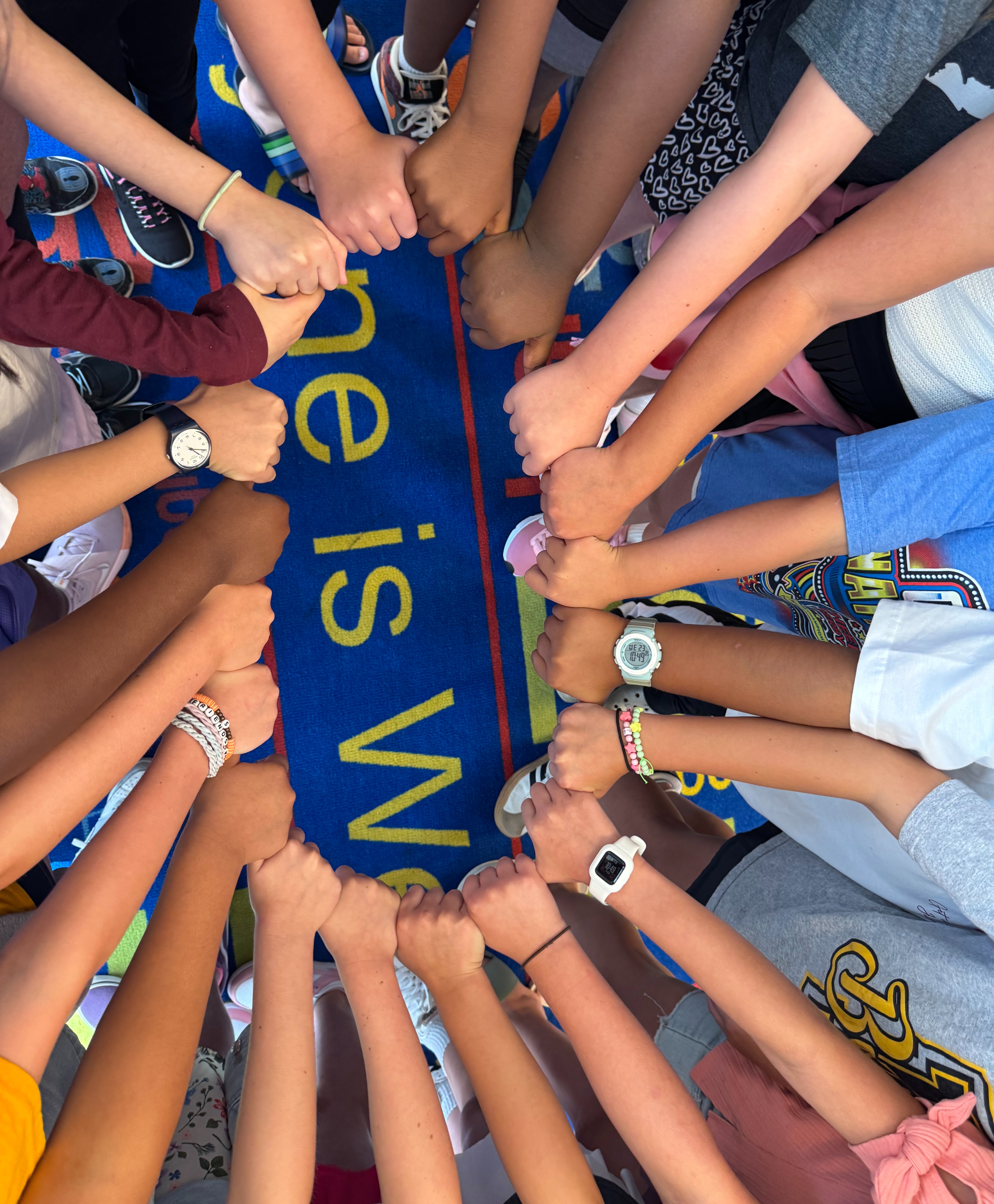 Students with their hands together in a circle