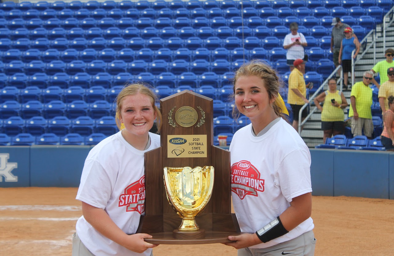 Two young women posing for a photo with a trophy.