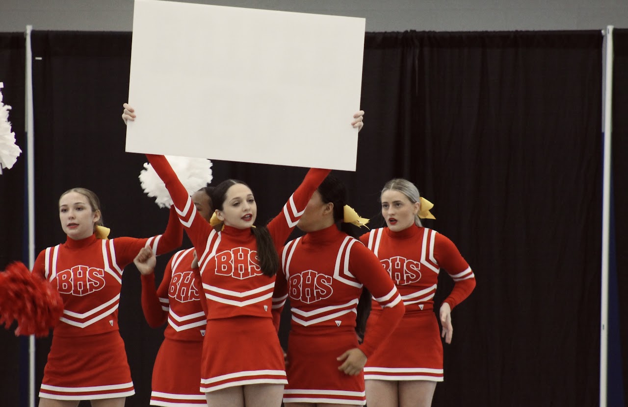 Cheerleaders with a sign and performing