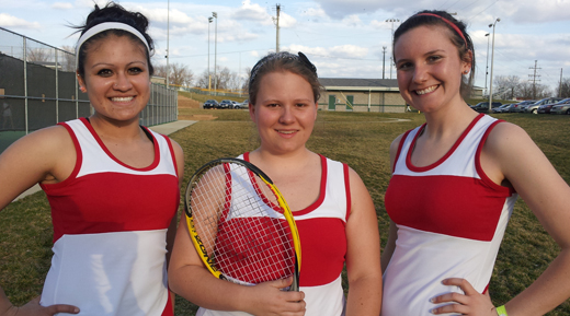 Three women wearing matching red and white tennis outfits, each holding a tennis racket.