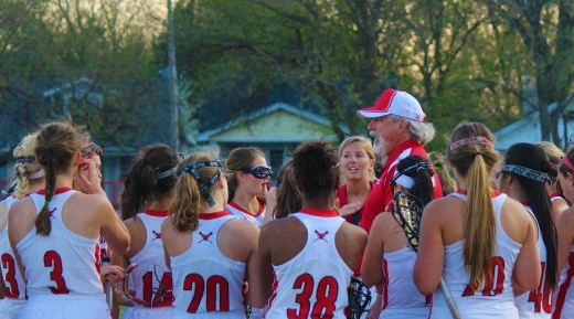 A team of women's lacrosse players gathered for a photo with their coach.
