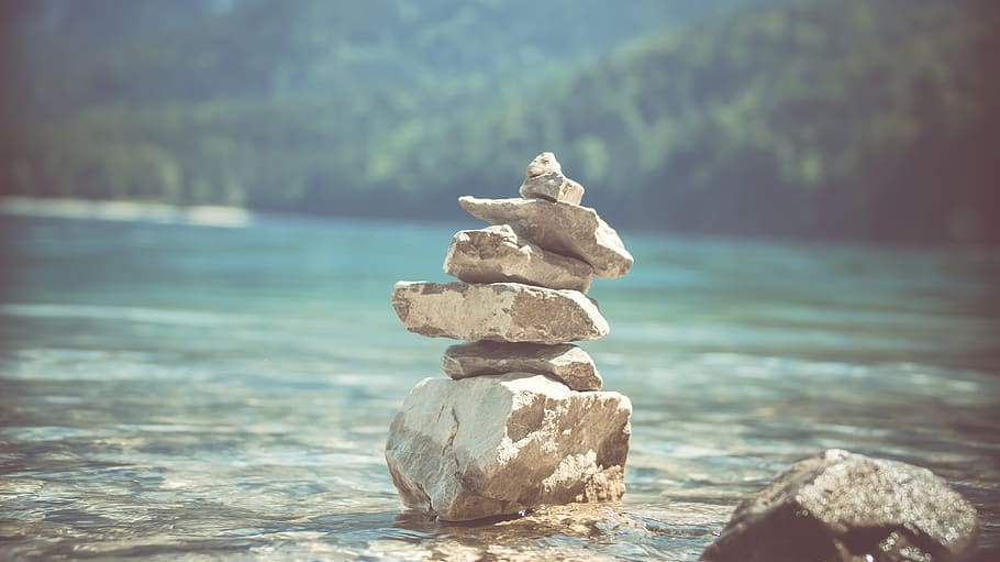 A serene stone stack by a tranquil body of water.