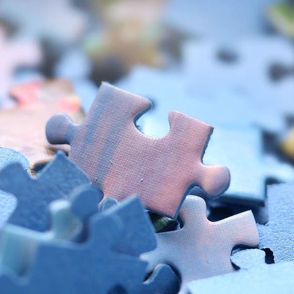 A jigsaw puzzle piece with a wooden texture against a blue background, surrounded by other puzzle pieces.