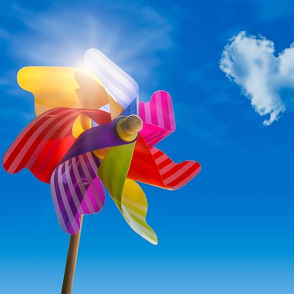 Colorful windmill against a clear blue sky with a few scattered clouds, capturing the essence of a bright and sunny day.