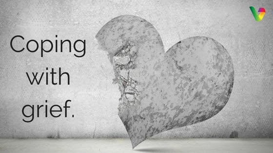 An image featuring a graphic of a heart, with the words 'coping with grief' overlaying it. The background is a textured concrete wall with the phrase 'grief' in capital letters underneath the heart.