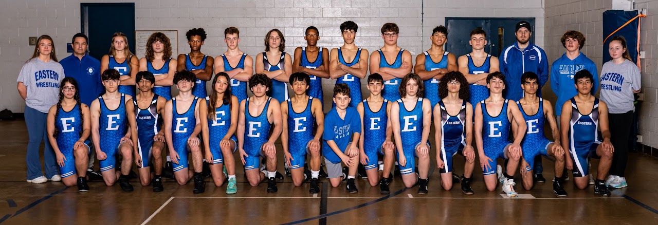 A group of young athletes poses for a team photo in their school's gymnasium.