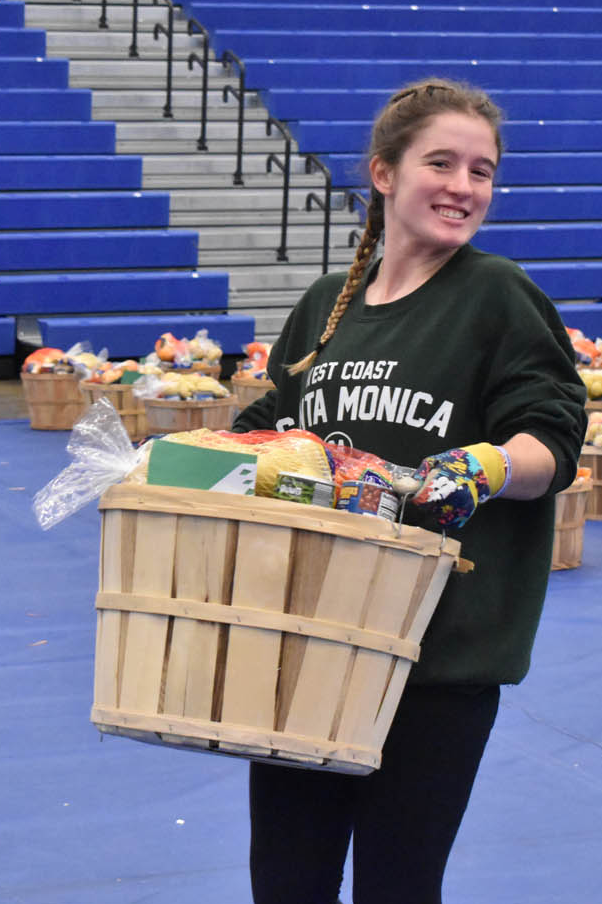 Student carrying basket of food to family