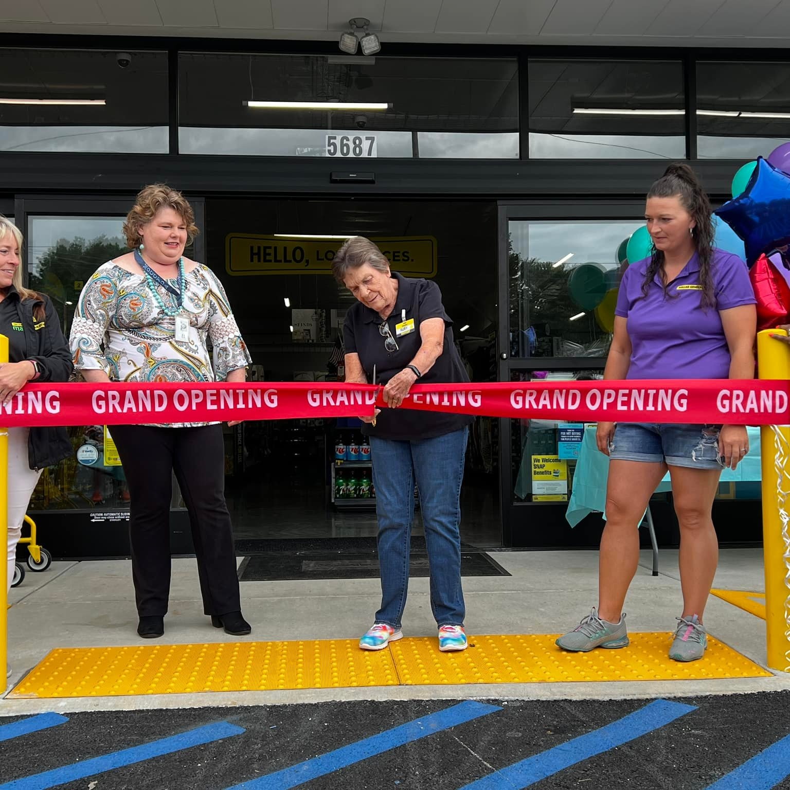 The grand opening day at Dollar General on HWY FF.  A woman in a black shirt cuts a red ribbon. 