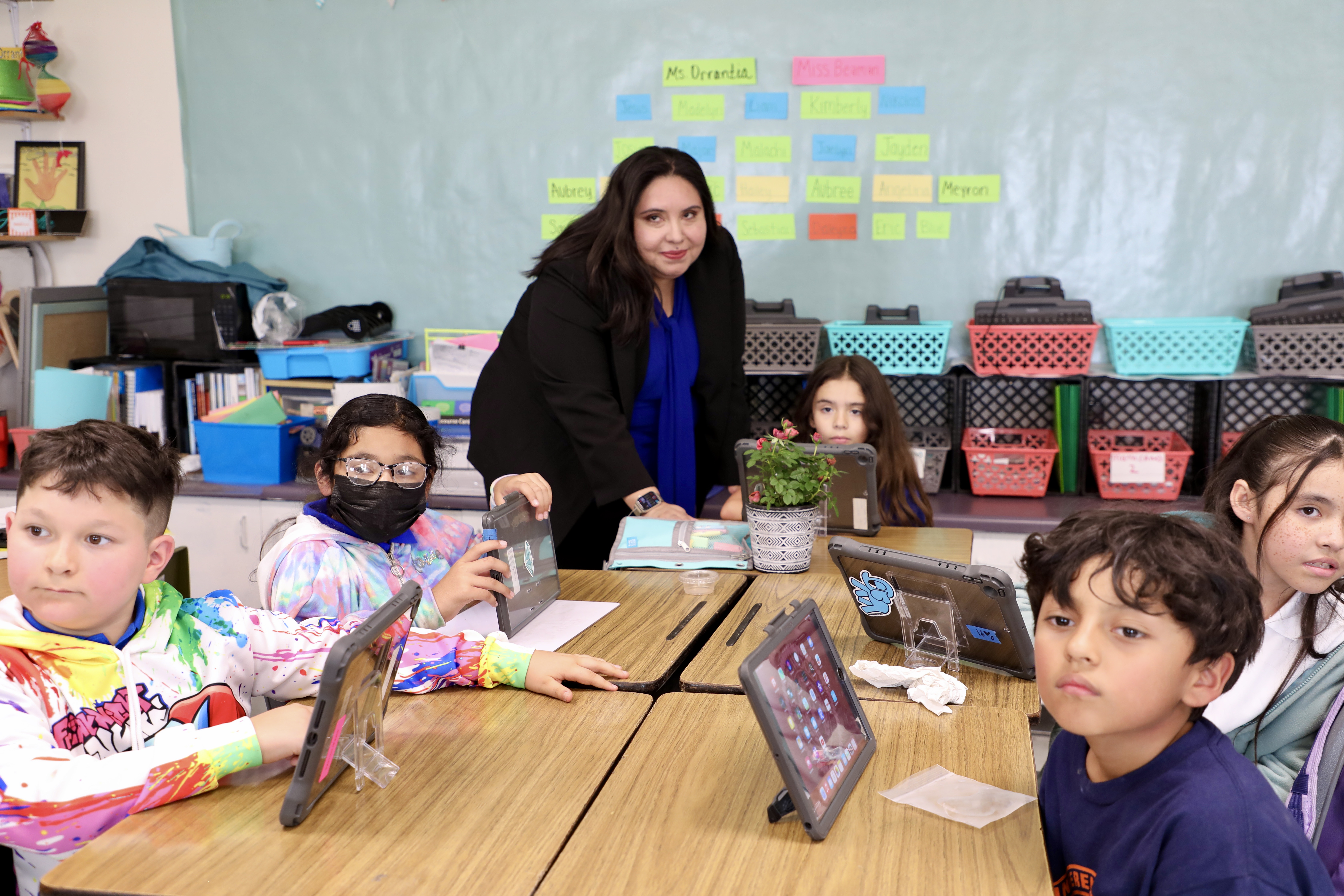 Principal standing around children seated at desks