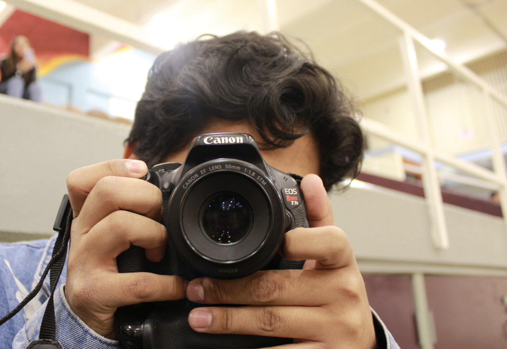 A boy taking a photo using a black Canon camera