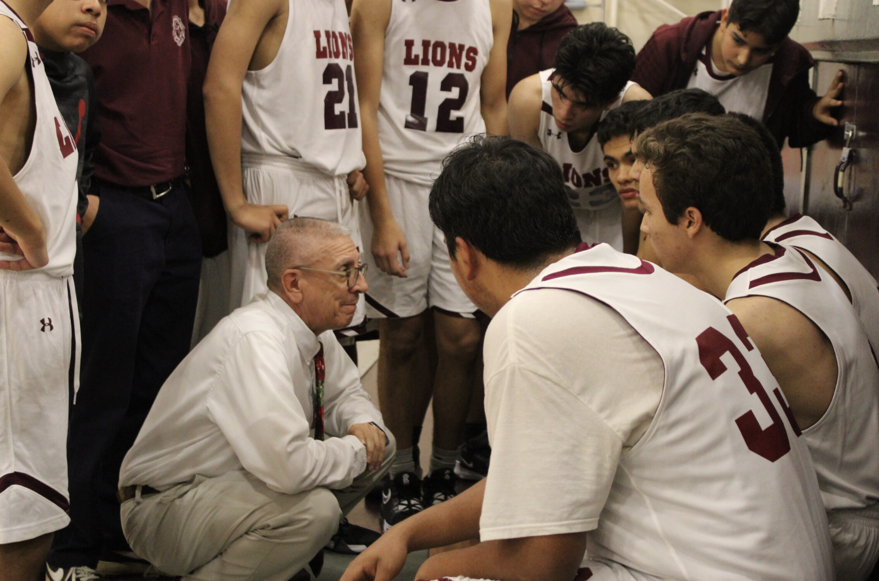 Lions basketball team listening to a teacher.