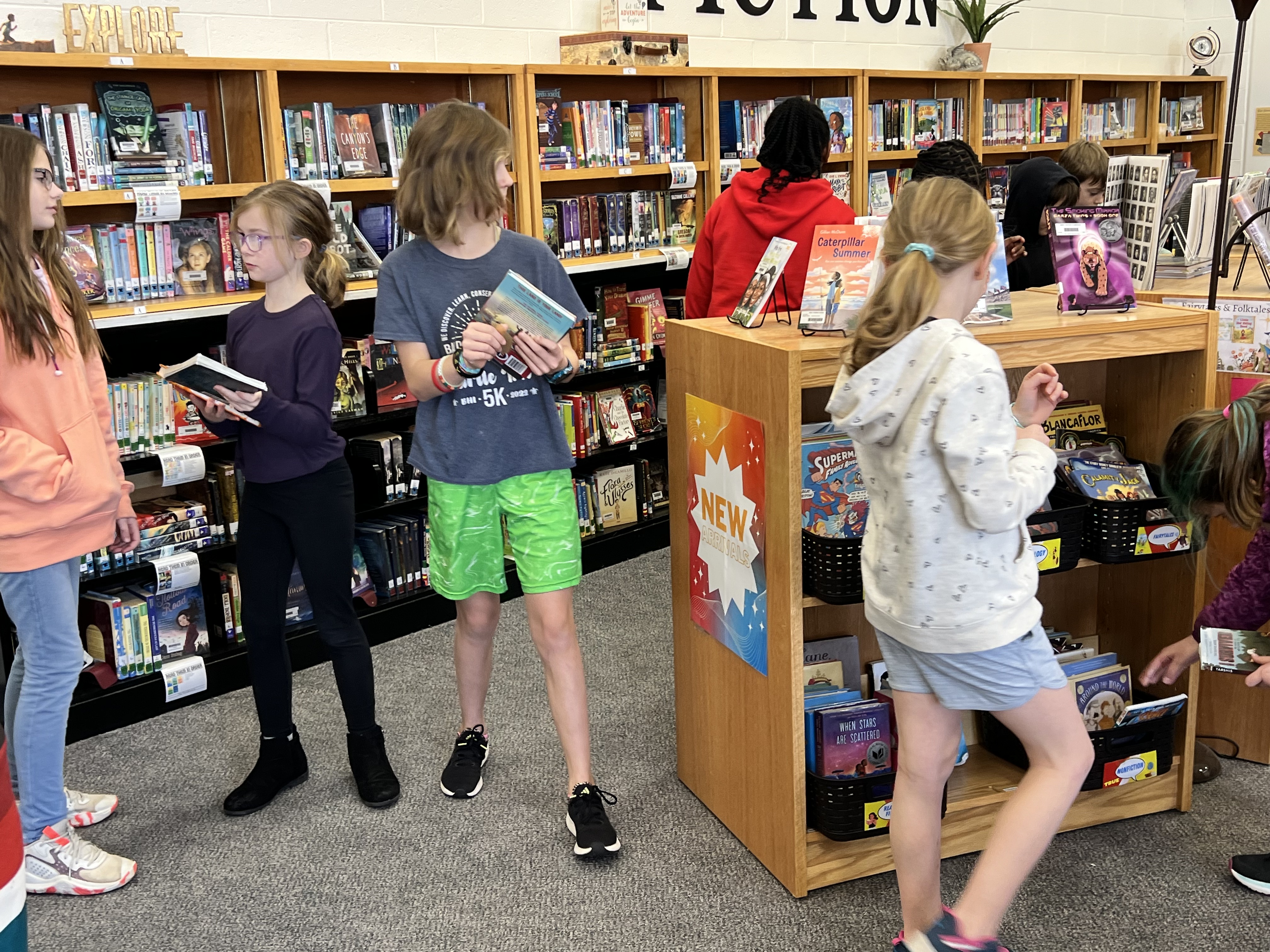 Elementary students explore library books.