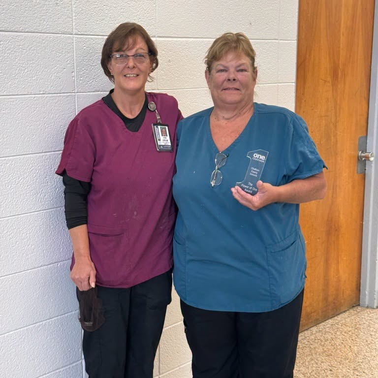 Staff member holding Power of One Award in hand.  