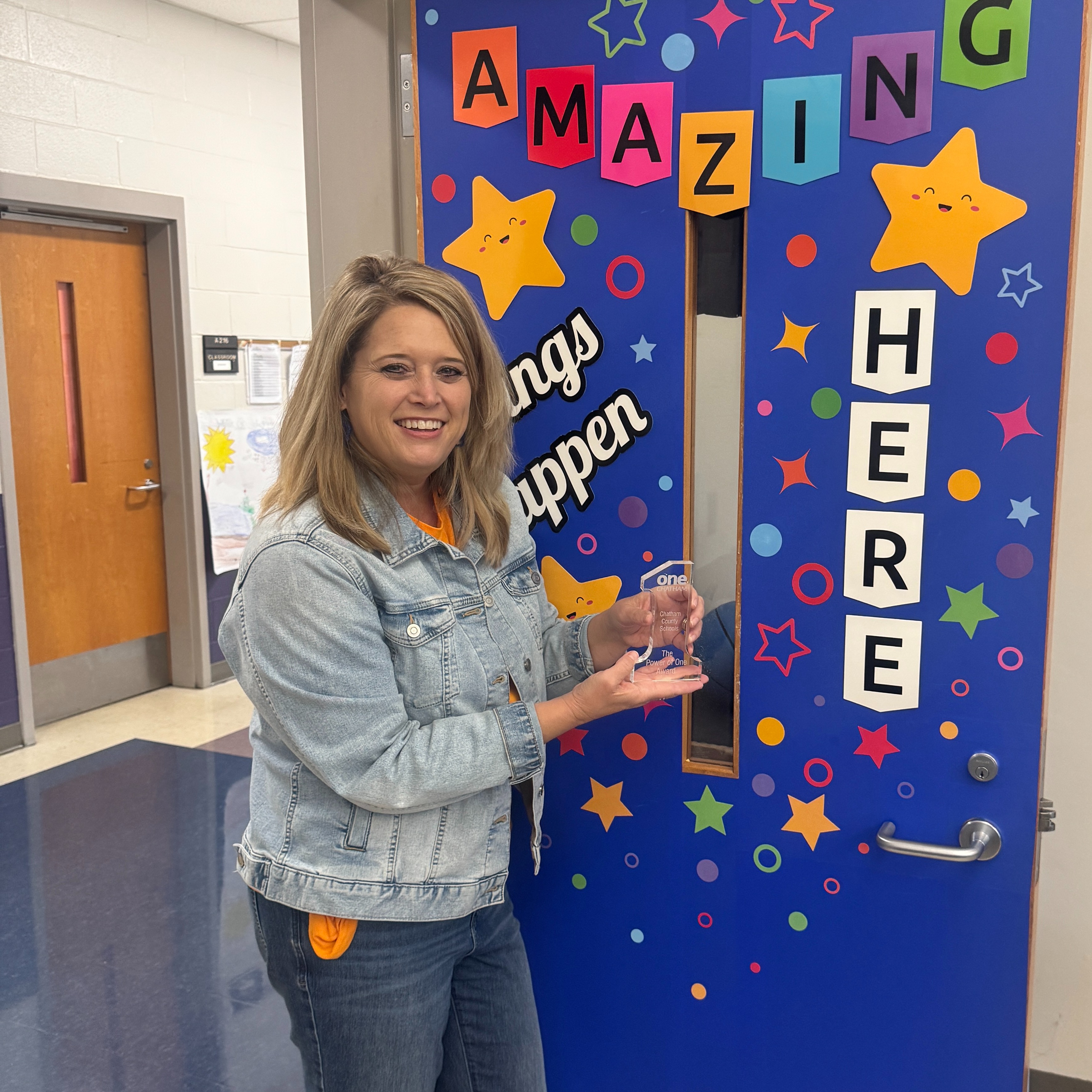 Staff member holding Power of One Award in hand.  