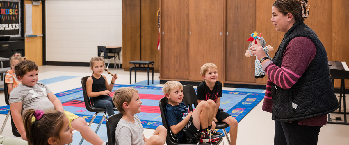 kindergarten students in class watching a teacher with a puppet