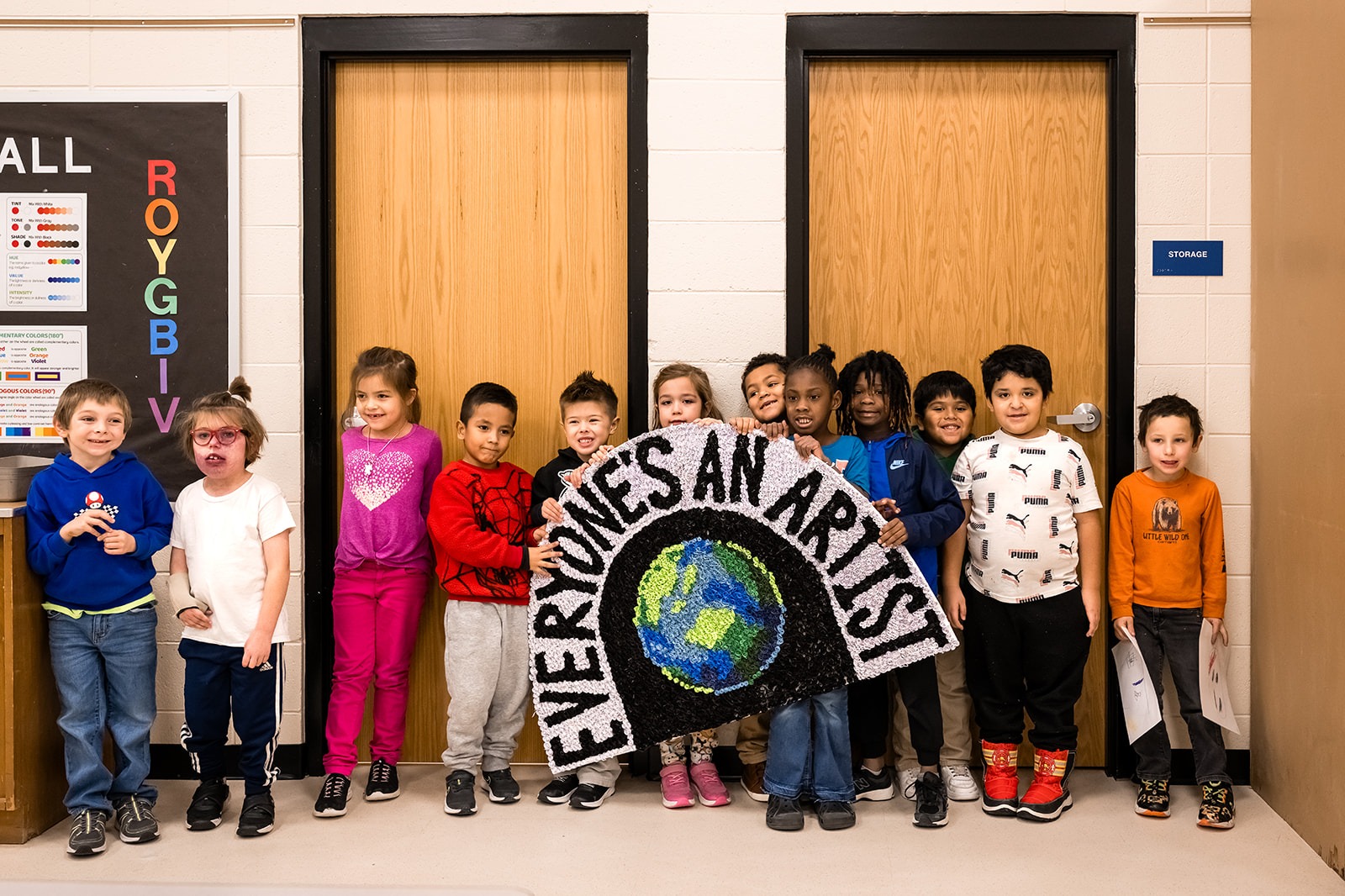 elementary school students holding an "everyone's an artist" sign