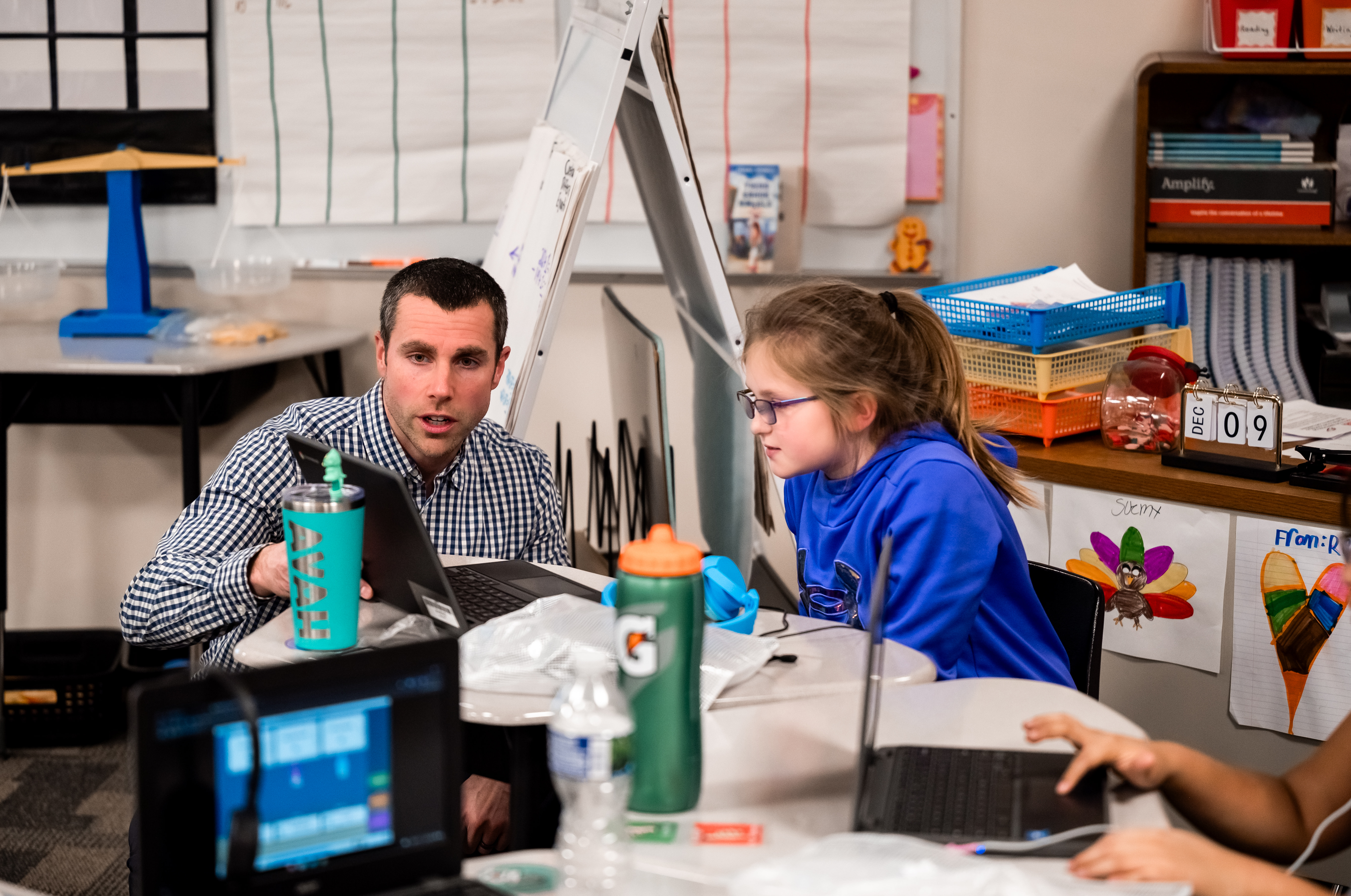 Left, Alex O’Connor, TOSA at Chegwin Elementary School; right a student being helped by Alex while using a laptop