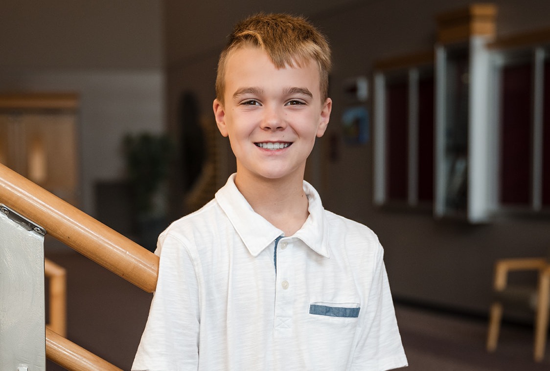 Student Lanson posing for a smile in the stairway of the school.