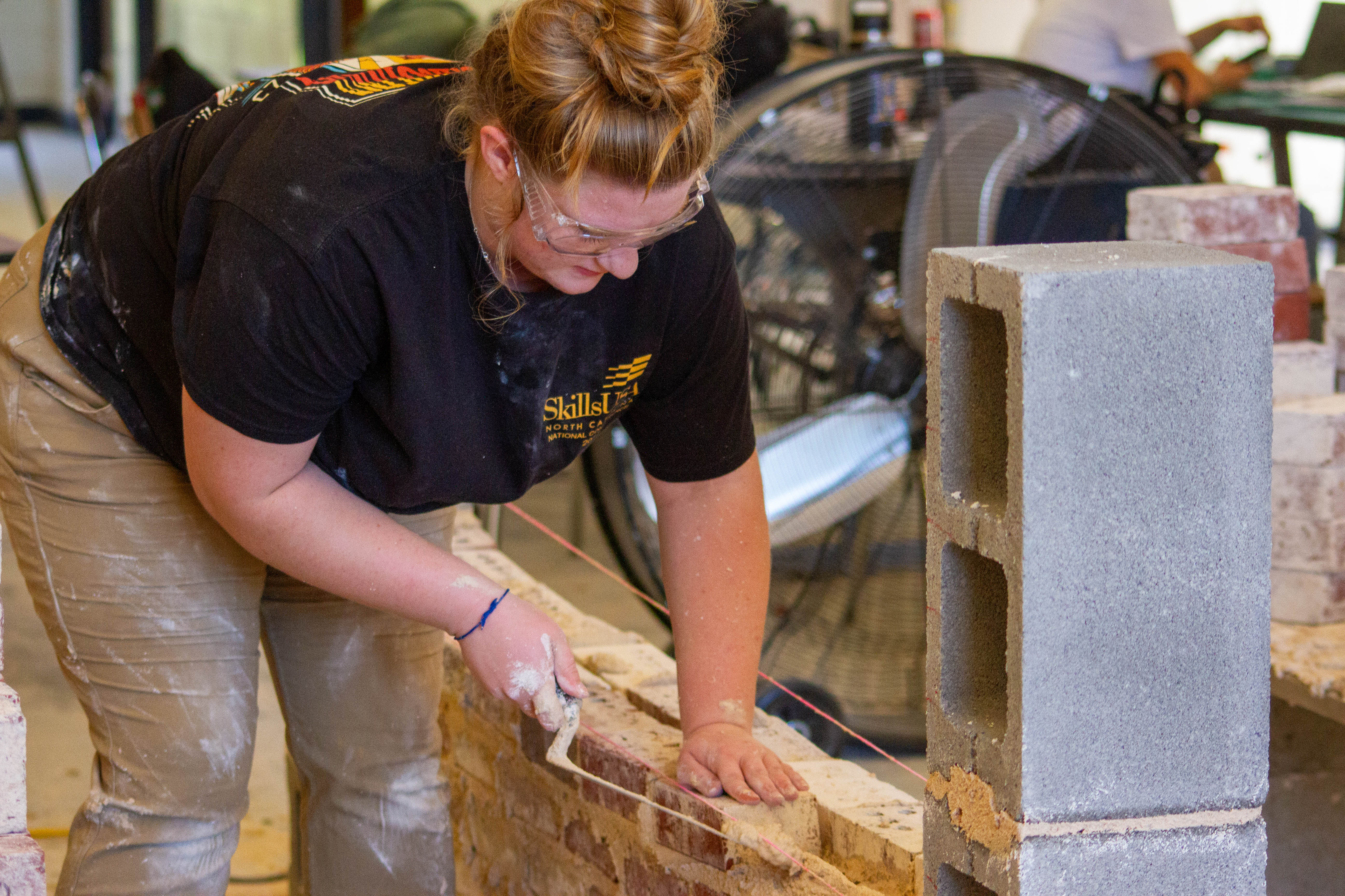 Christina C. practices laying a row of bricks in Masonry class at LCHS