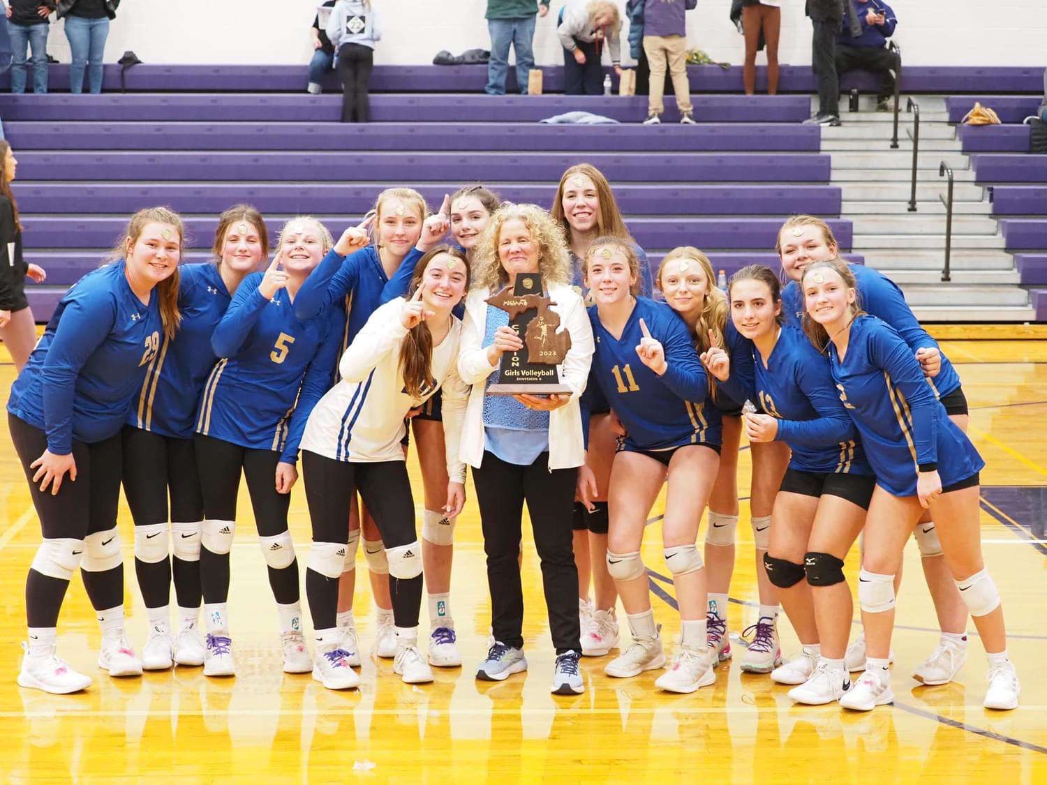The Onekama Portagers 2023 district champion volleyball team celebrates their district finals victory.