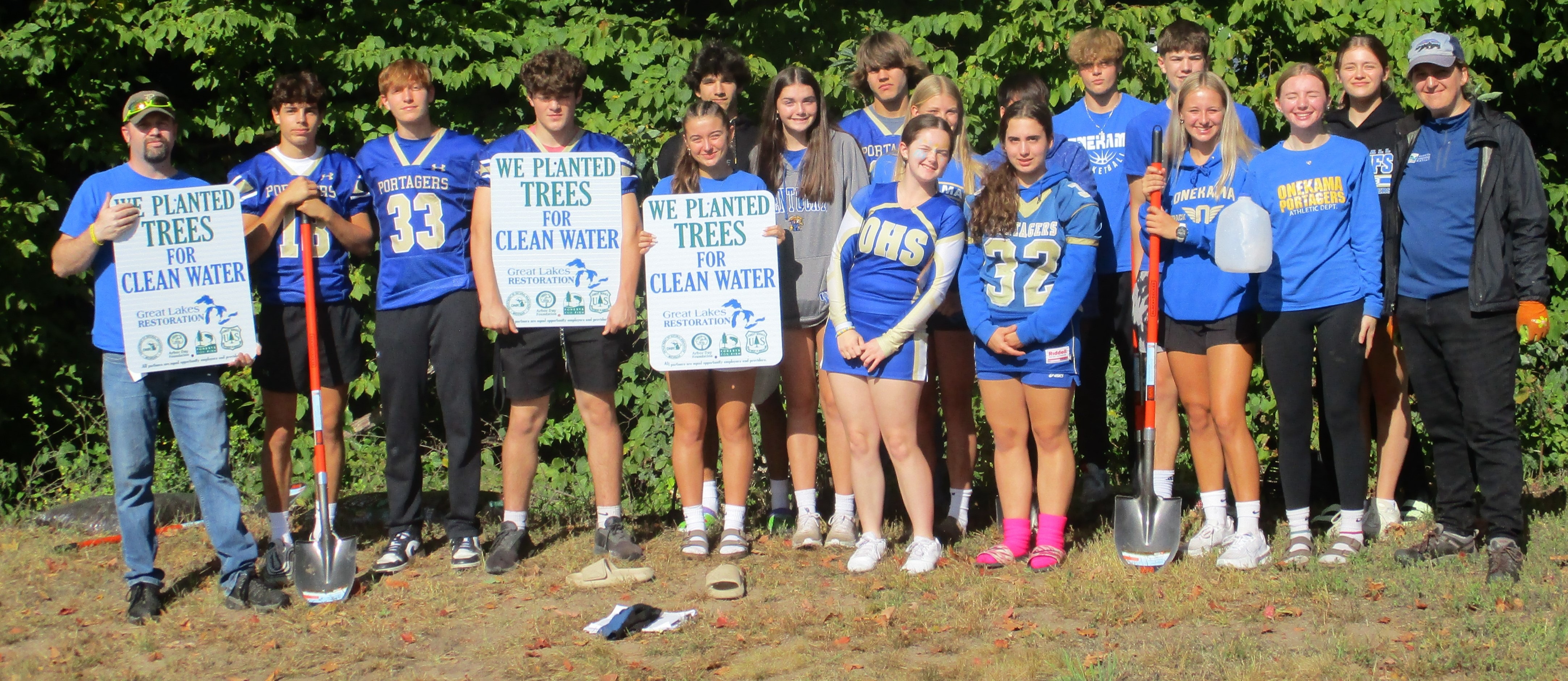 Mr. Matt Lonn poses with high school students after planting new trees on campus.