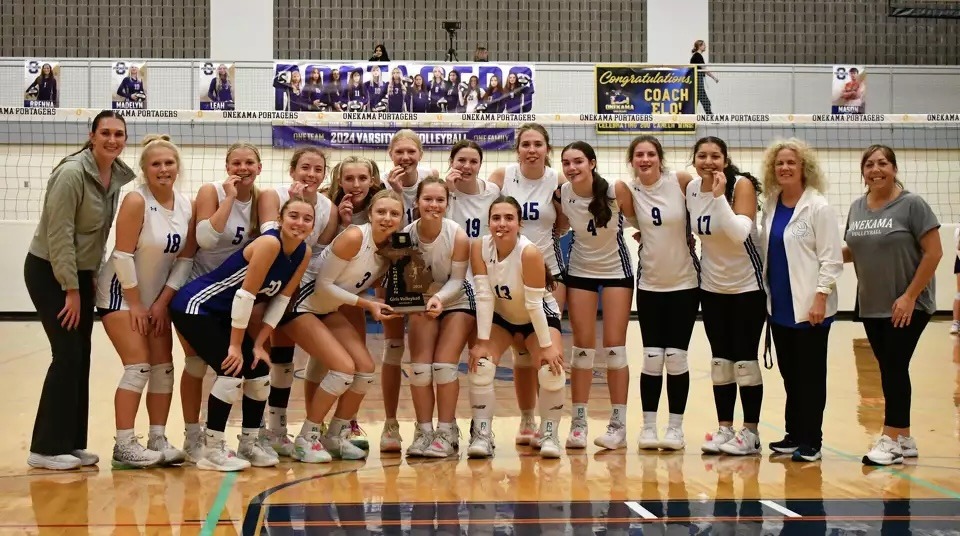 The Onekama Portagers 2024 district champion volleyball team celebrates their district finals victory.