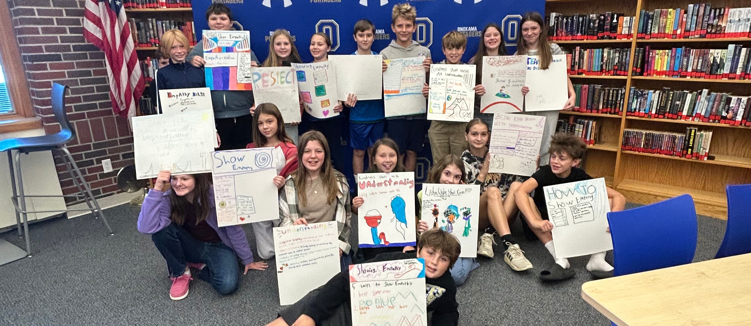 Middle school students pose with their empathy posters from Mrs. Burtch's class.