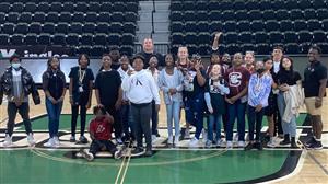 A group of basketball players and coaches gathered on the court for a team photo.