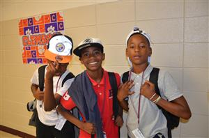 Three young students posing for a school photo, smiling and showing off their school spirit.