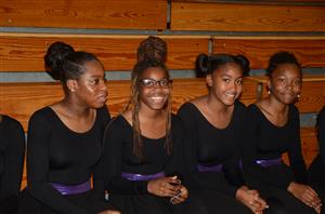 A group of cheerful young women in black attire, posing together for a photo with big smiles.