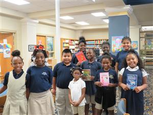 couple of kids holding a book each 