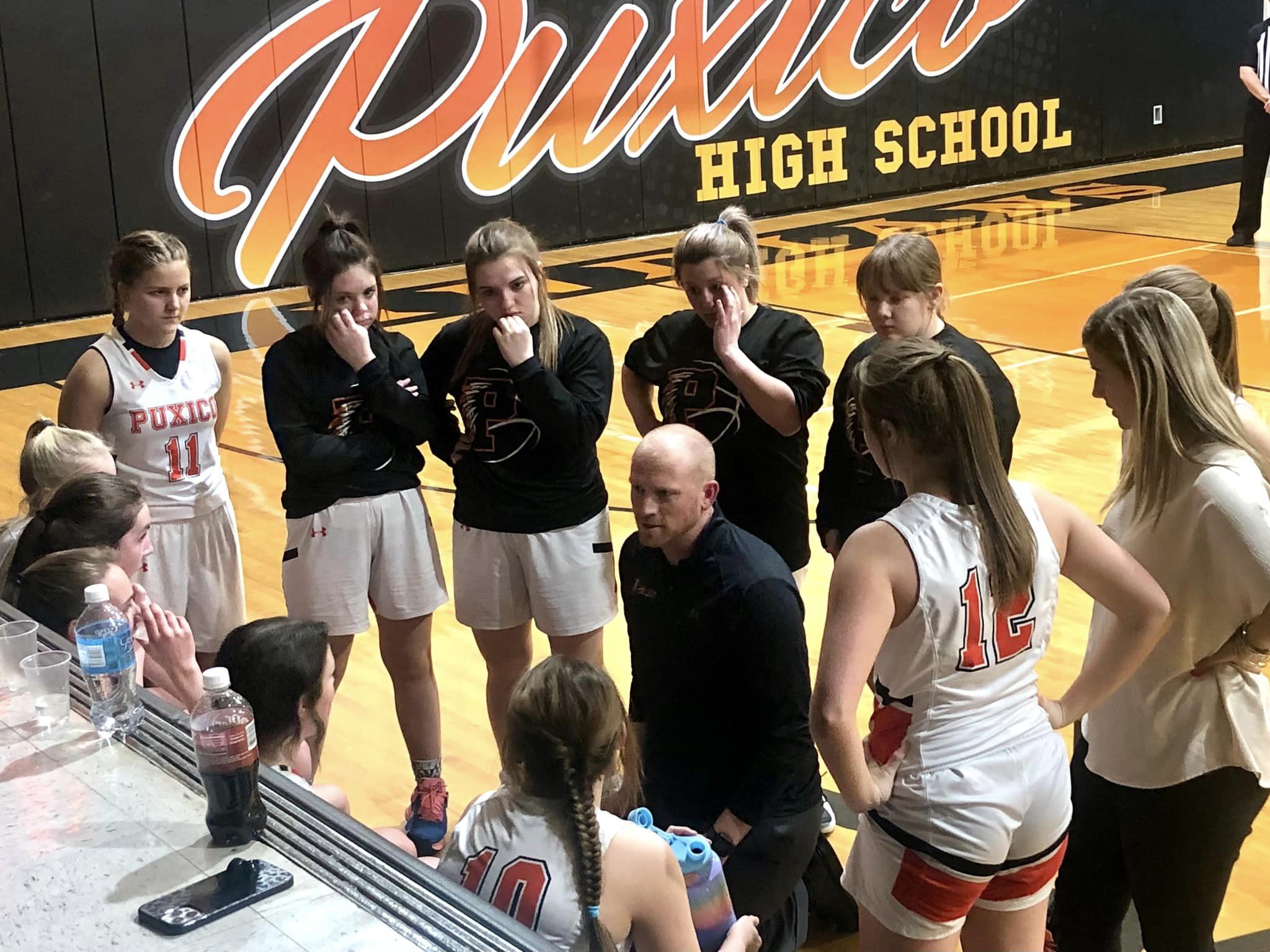 girls basketball team huddles around the head coach during a time out