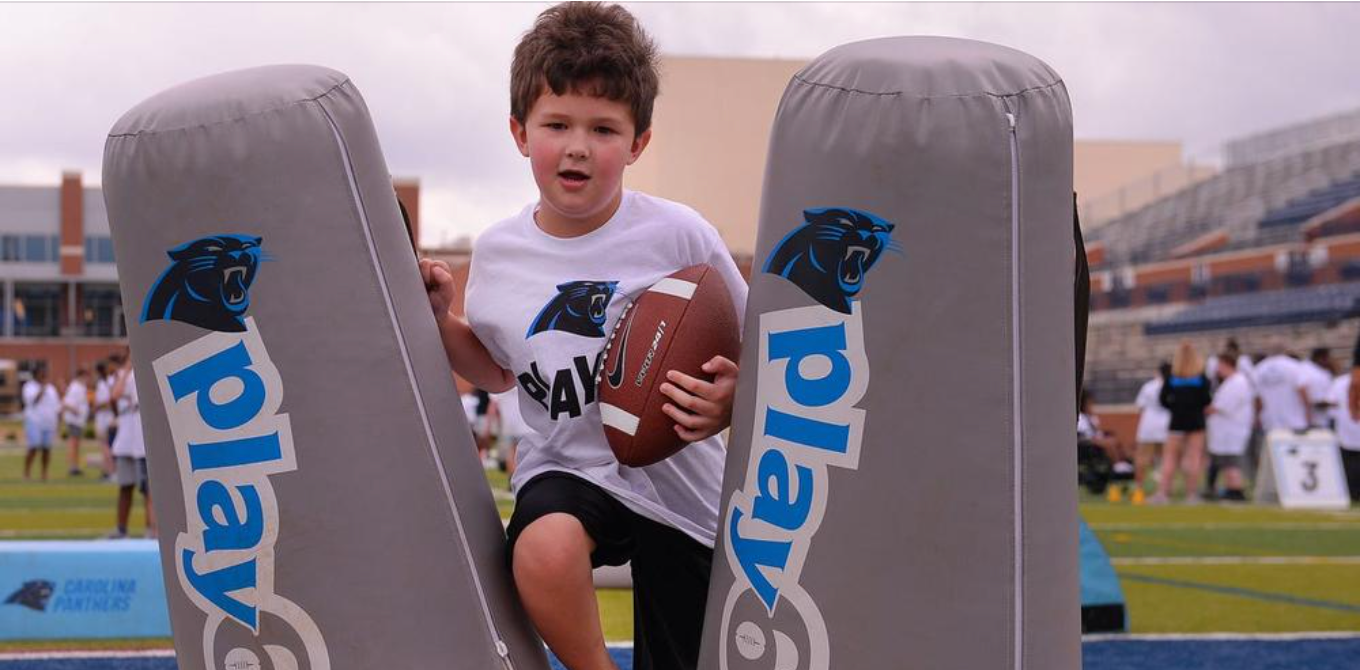 child with a football at panthers training 