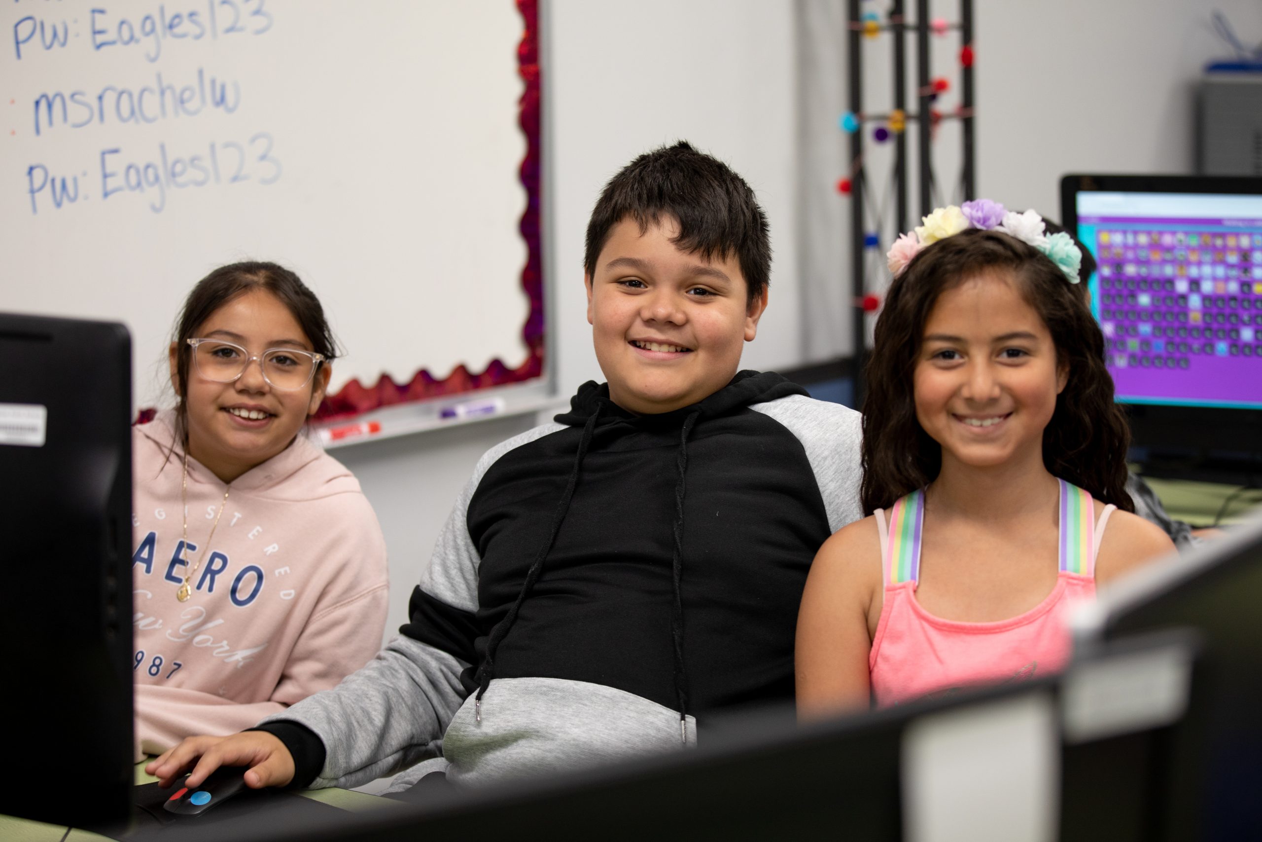 Students smiling while sitting around computer