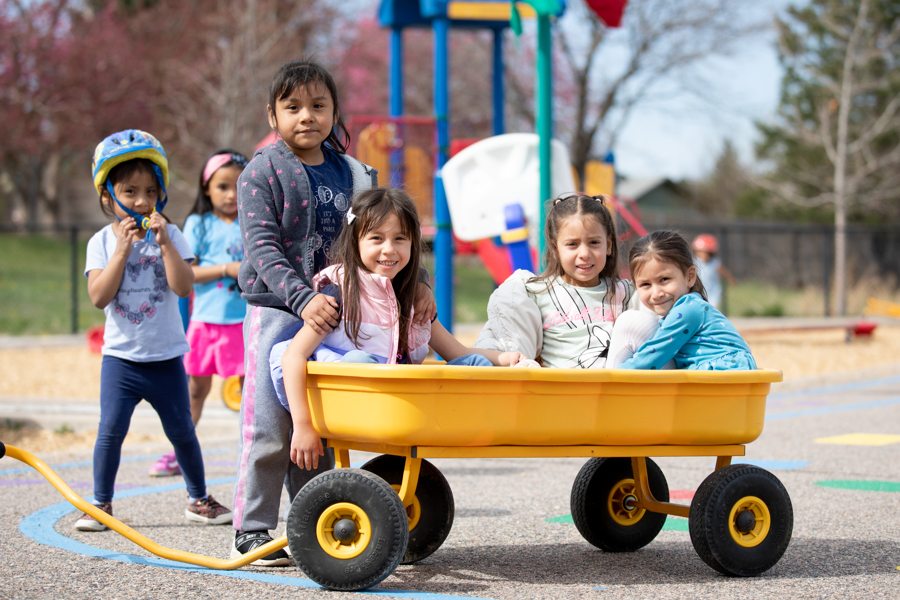 Group of ECE students playing with a wagon on the playground