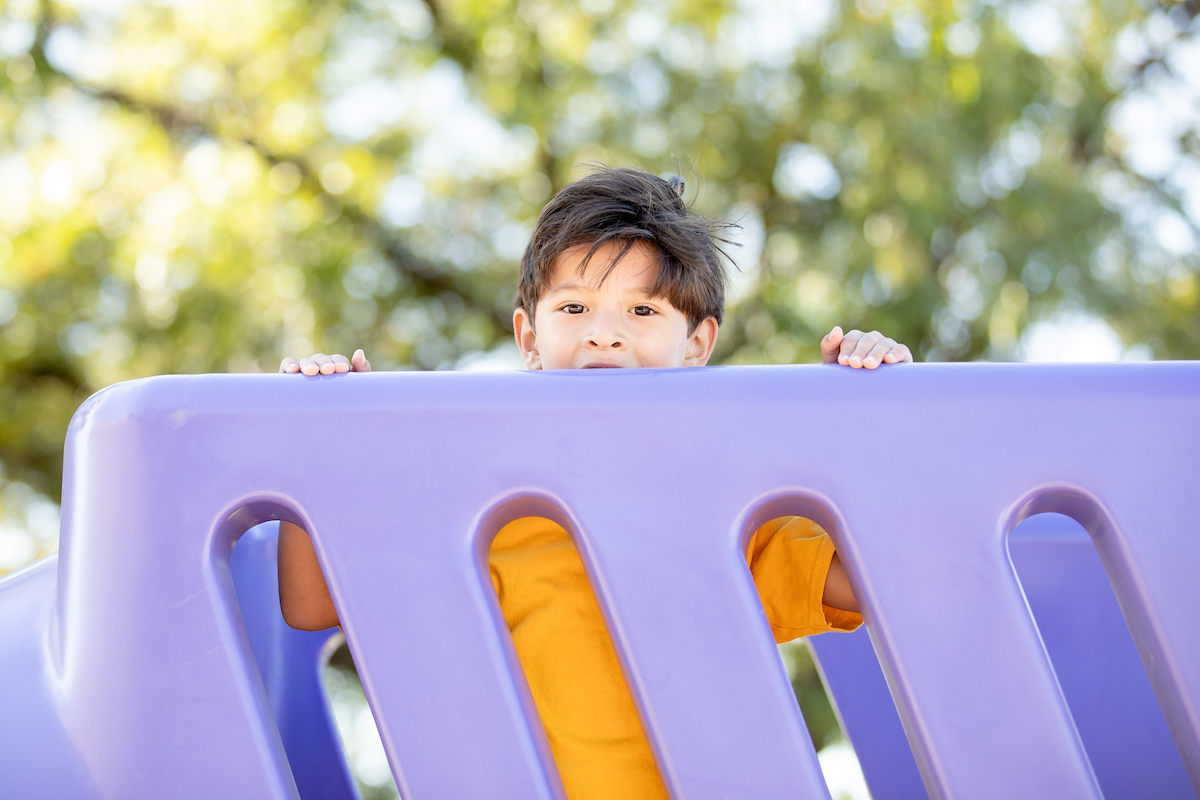 student peeking over playground bridge