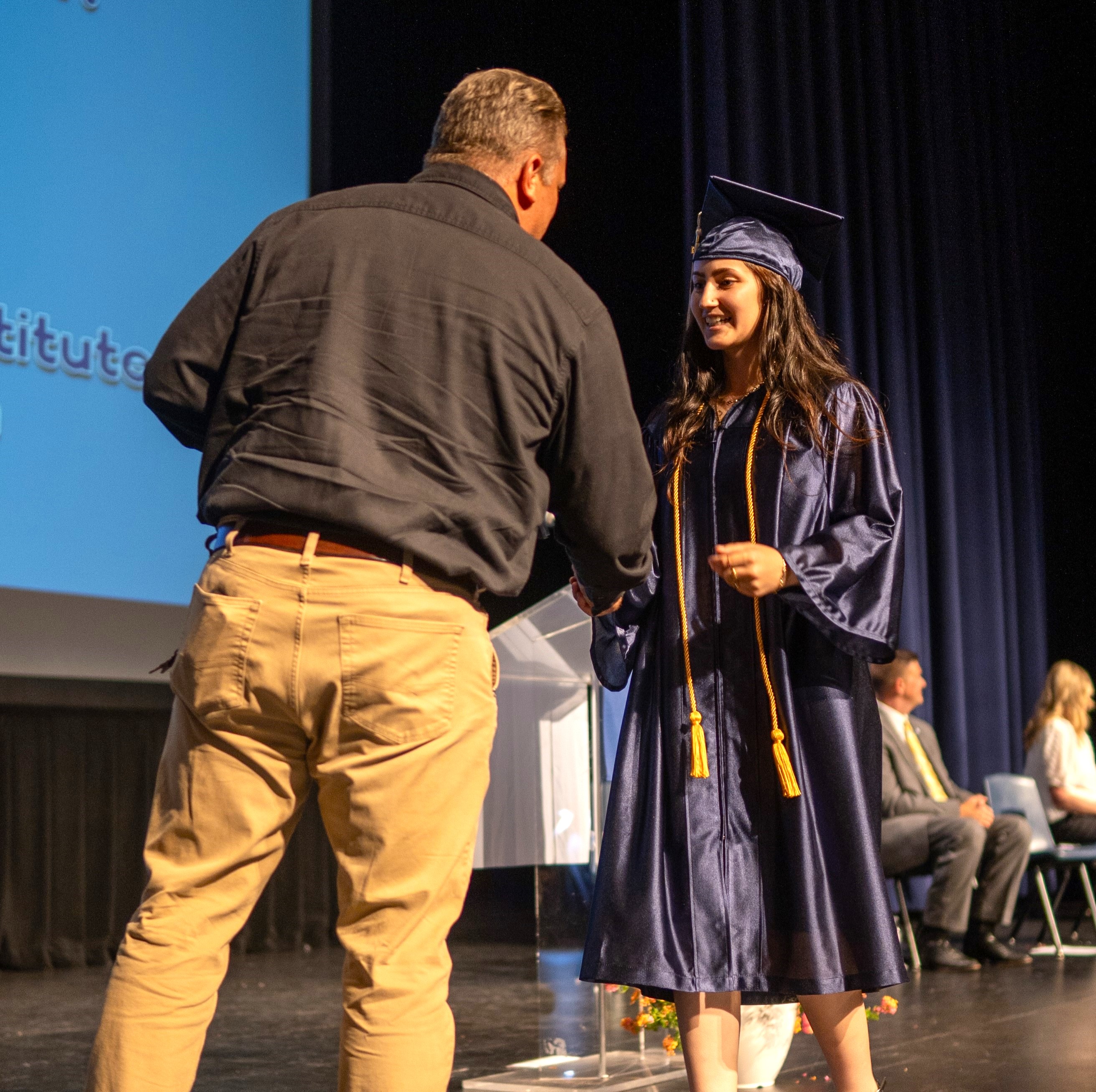 a board member hands out a diploma 