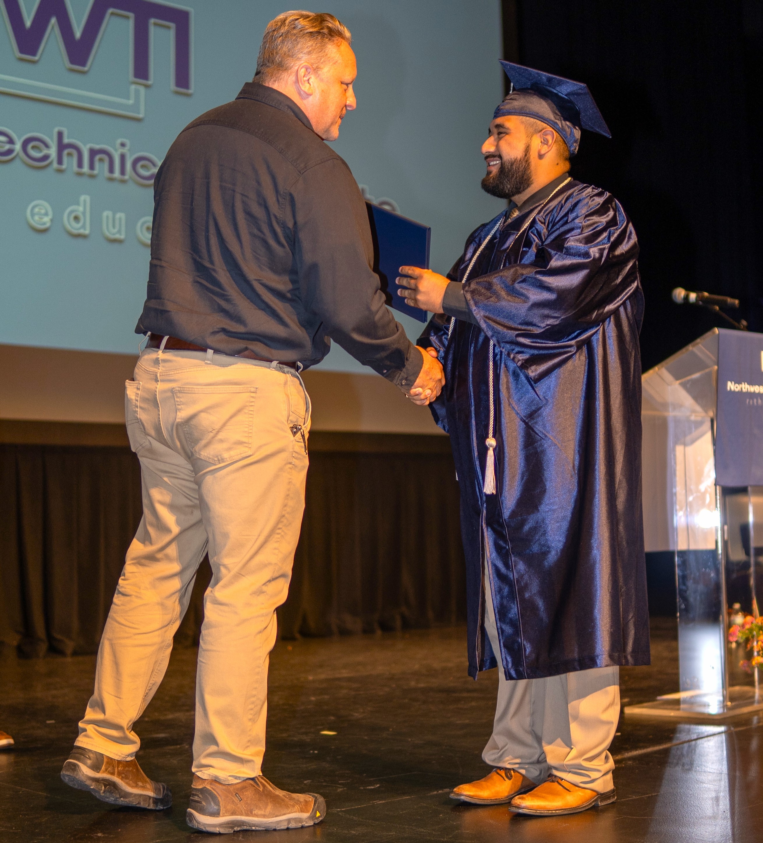 board member shakes hands with a graduate