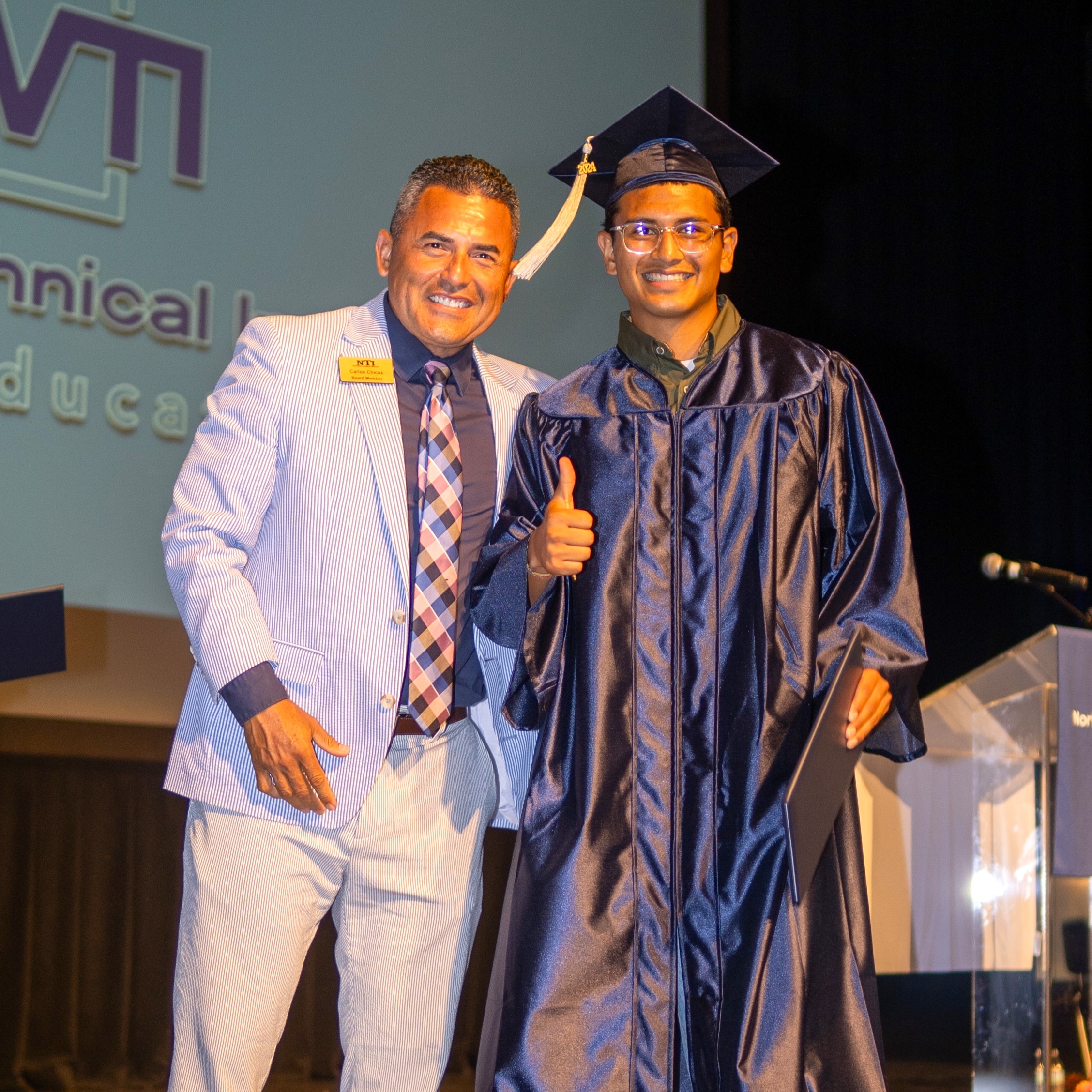 carlos chicas poses onstage with a grad